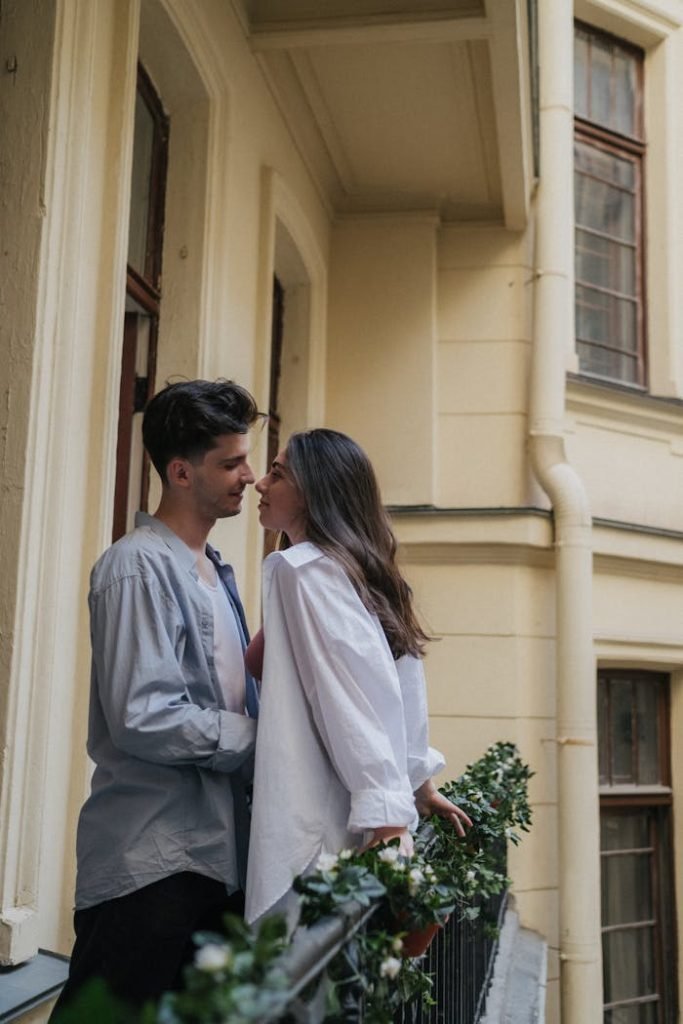 Couple sharing an intimate moment on a charming balcony, exuding romance.